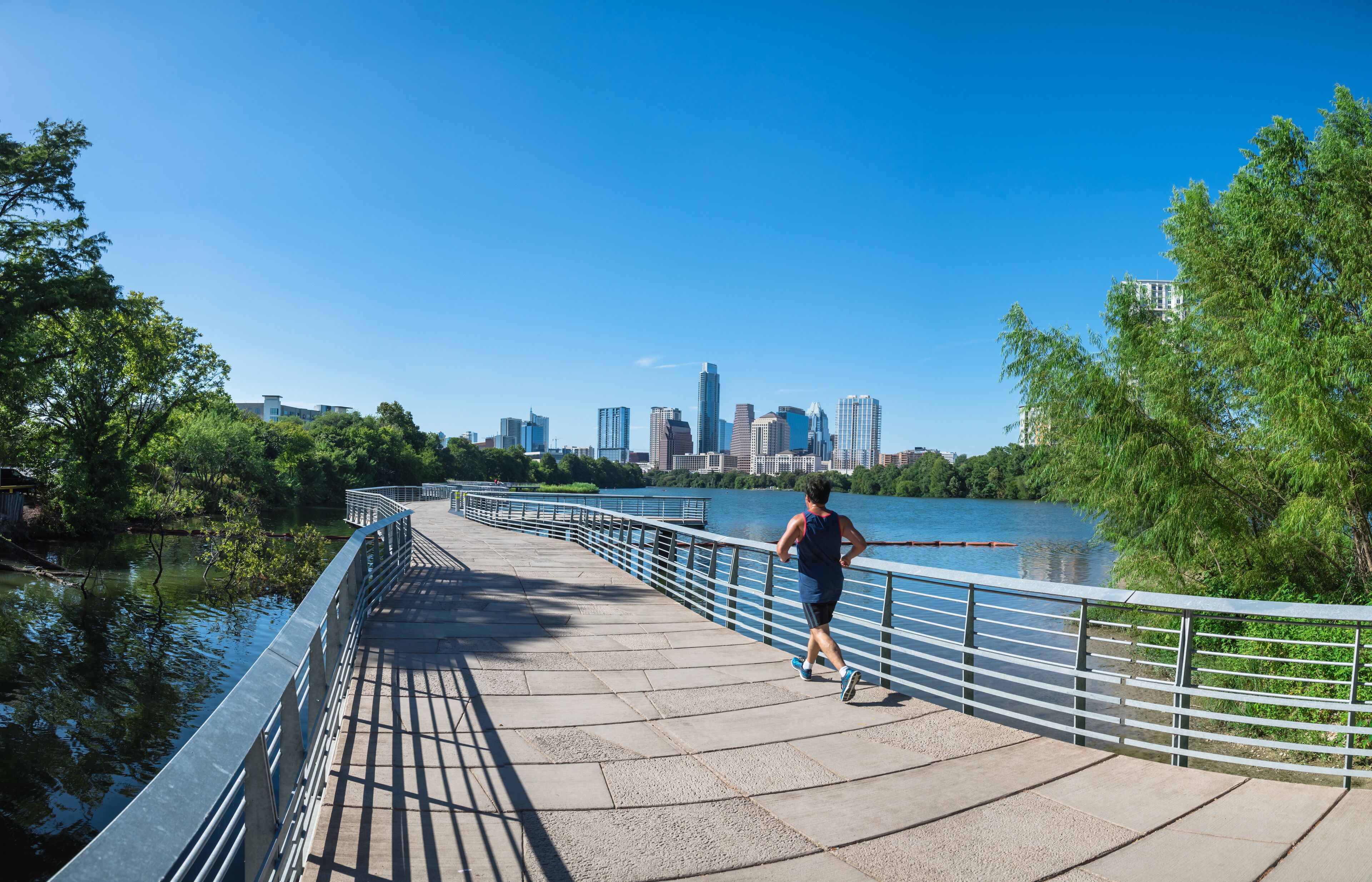 A runner on a bridge with a city skyline in the background.