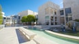 A modern architectural complex with a central courtyard, outdoor seating, and a water feature.