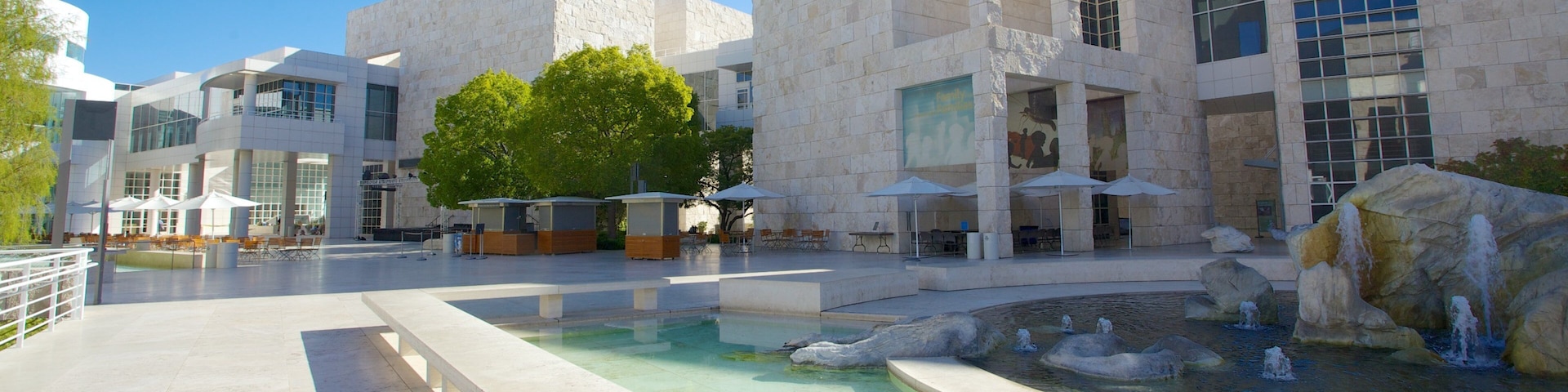 Un ensemble architectural moderne doté d’une cour intérieure, d’un espace extérieur aménagé pour s’asseoir et d’un élément décoratif aquatique.