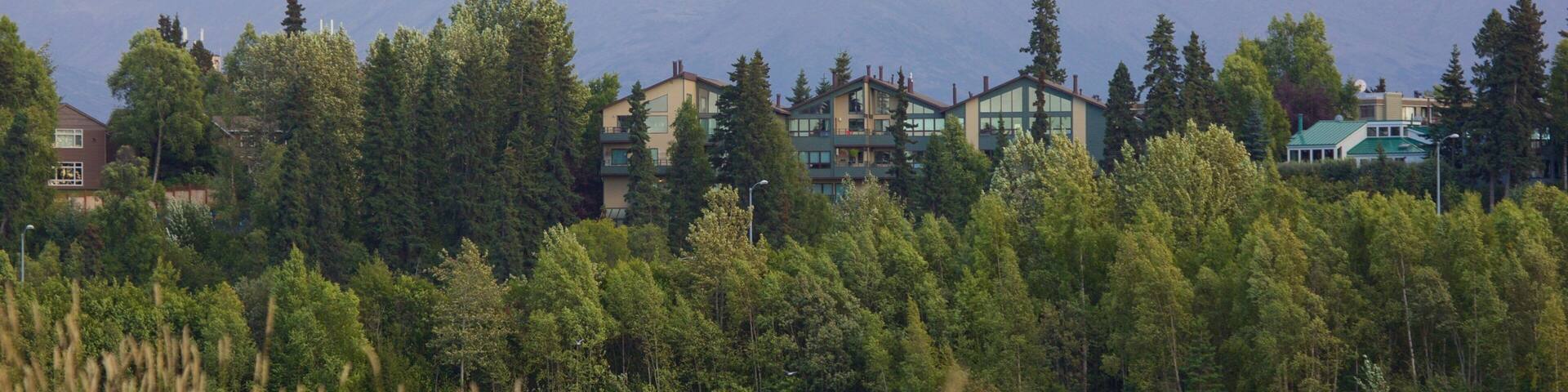 A lake with buildings and mountains in the background.