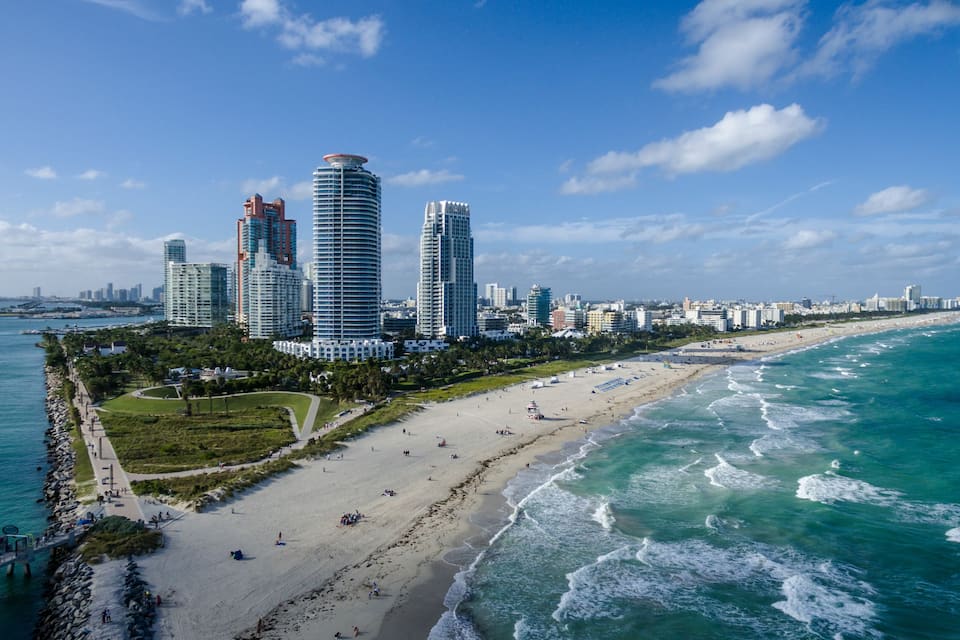 A coastal cityscape with high-rise buildings, a sandy beach, and the ocean.