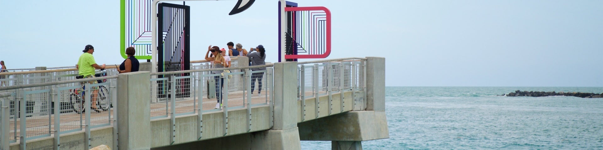 A pier with a sign reading "South Pointe Pier" and people walking along it.