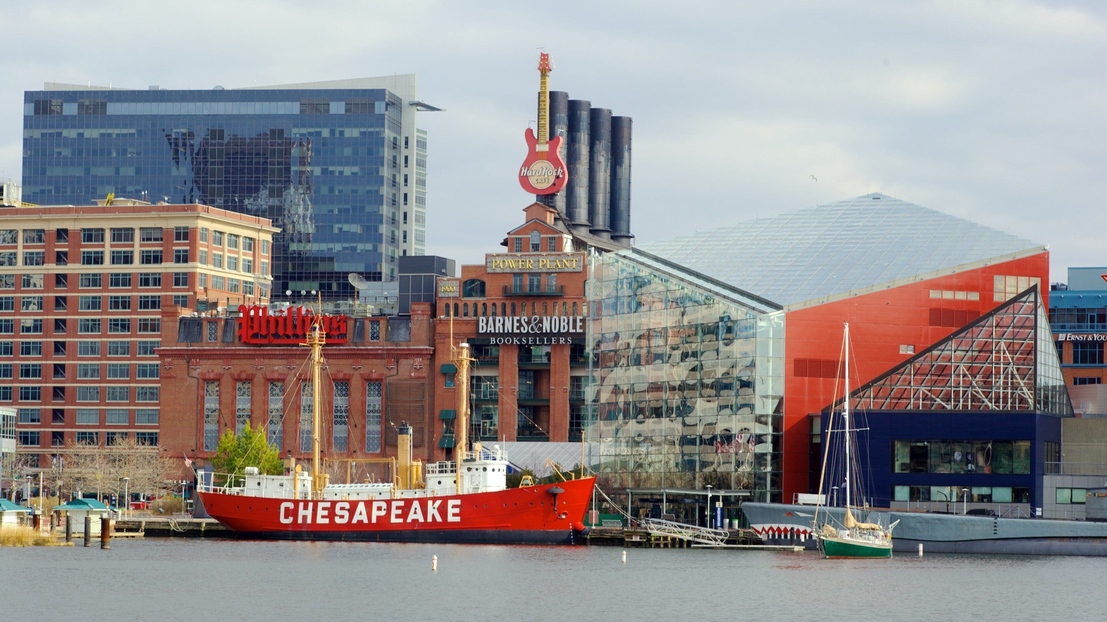 Un barco rojo llamado Chesapeake atracado en un puerto, con un paisaje urbano de fondo.