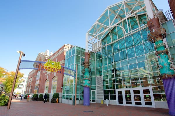 A modern building with large glass windows and a unique sculpture in front.