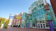 A modern building with large glass windows and a unique sculpture in front.
