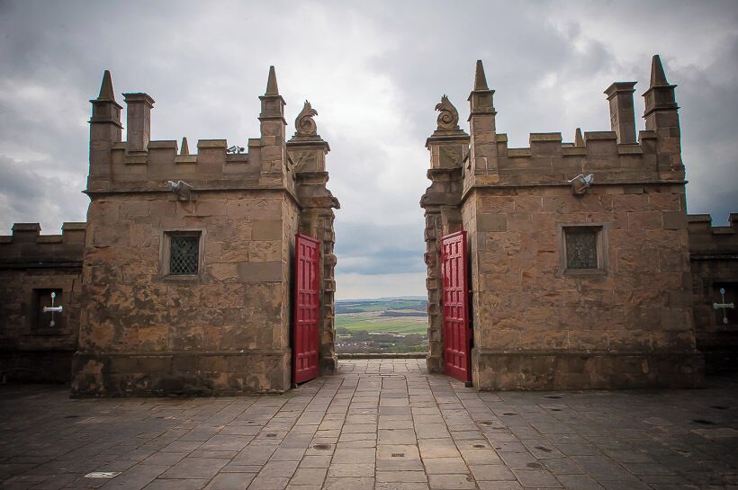 A stone castle with red doors and battlements.