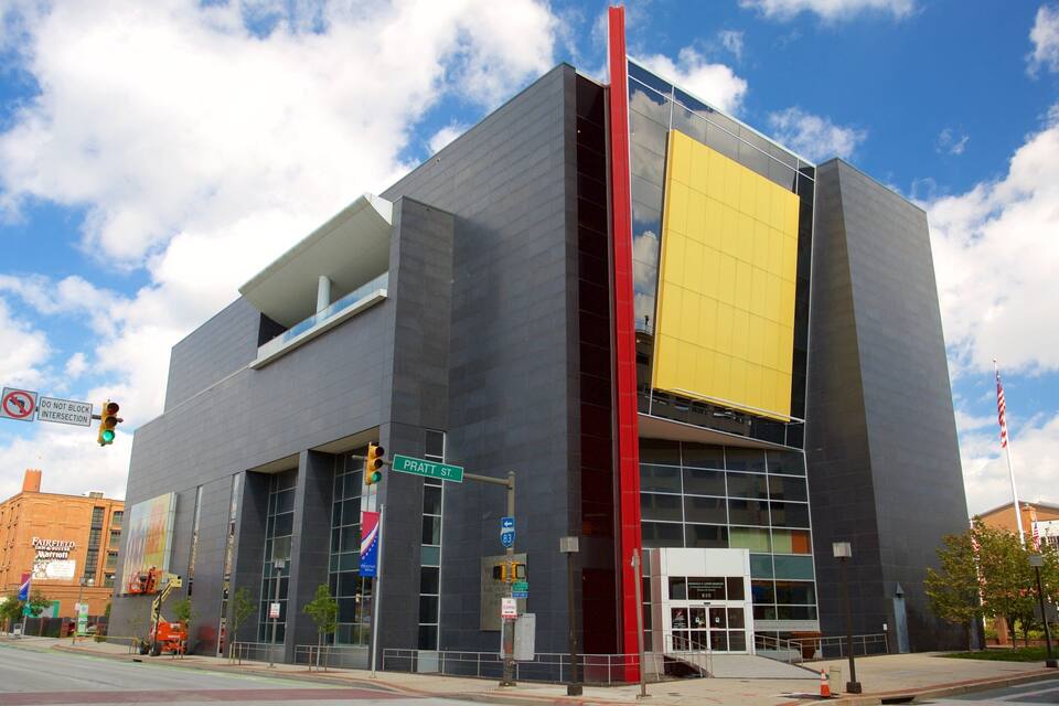 Un bâtiment moderne à la façade jaune, agrémenté d’un élément vertical rouge et d’une enseigne indiquant « Pratt Street ».
