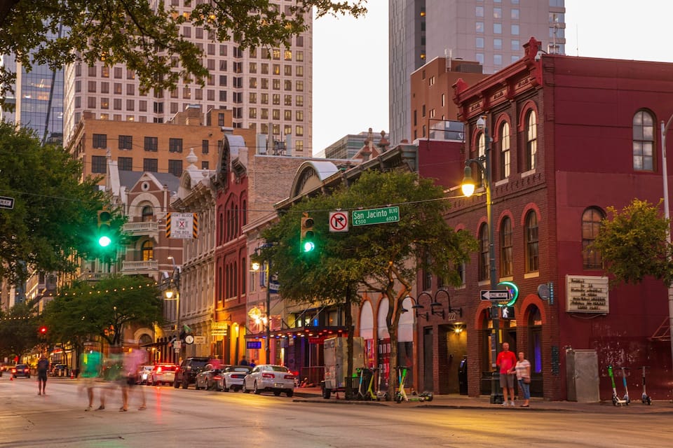 A city street with historic buildings, traffic lights, and a 'One Way' sign.