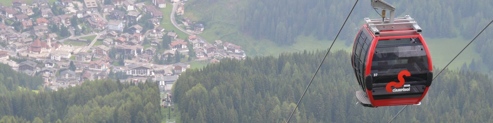Un teleférico sobre un paisaje montañoso con una ciudad en la parte inferior.