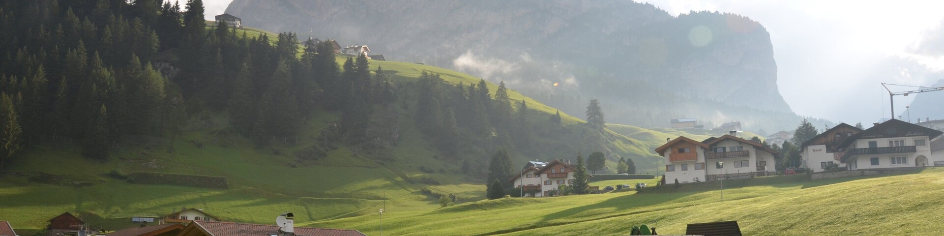 A rural village with houses, a large mountain, and a clear sky.
