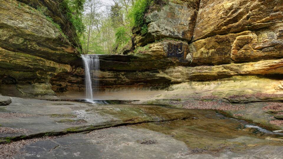 A waterfall cascading down a rocky gorge surrounded by lush greenery.