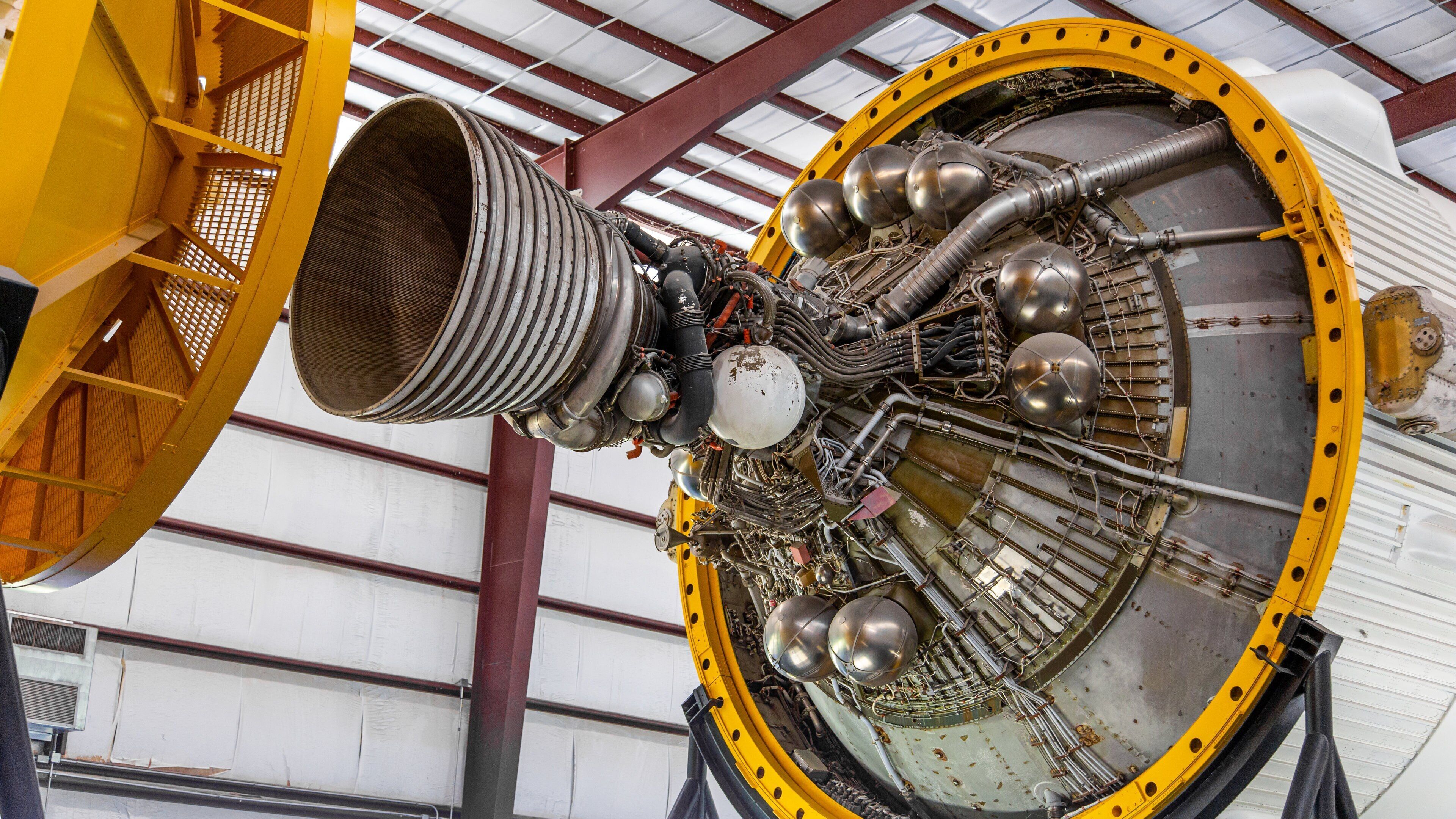 A large, complex mechanical structure with yellow and silver components, likely part of an aerospace vehicle.
