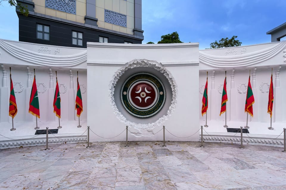 Una sala ceremonial amb un emblema central, flanquejada per banderes a ambdós costats.