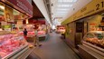 A supermarket interior with meat display cases, a bakery, and a sign for 'Rosi Okindegia'.