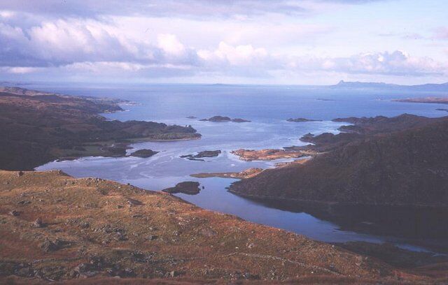 A coastal landscape with rocky terrain and a calm sea.