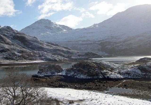 A snowy landscape with a lake and mountains.