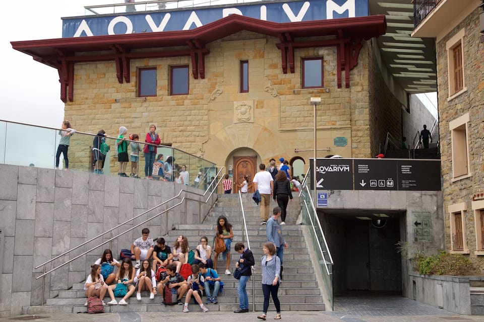 A stone building with a sign reading "AQUARIUM" and a staircase leading to an entrance.