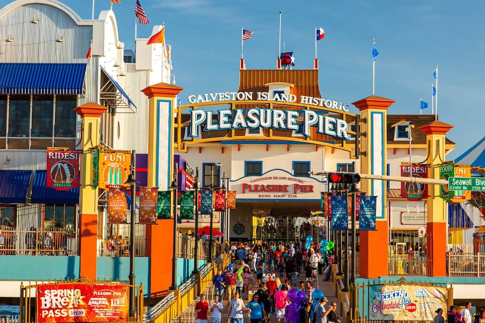 Entrada del Muelle del Placer con banderas, letreros y una multitud de gente.