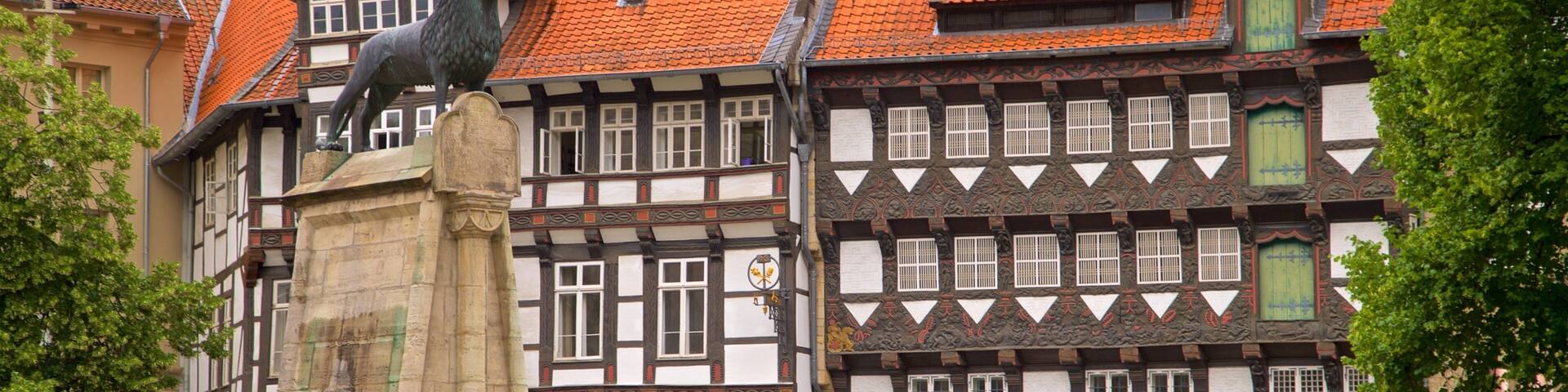 A traditional half-timbered building with a statue of a bear on a pedestal in front.