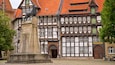 A traditional half-timbered building with a statue of a bear on a pedestal in front.
