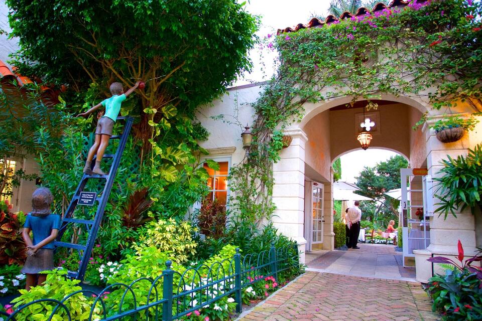A garden with a statue, a ladder, and a person climbing a tree.