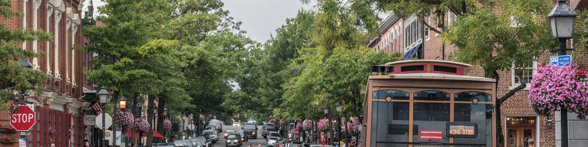 Um elétrico numa rua da cidade com carros, pedestres e edifícios.