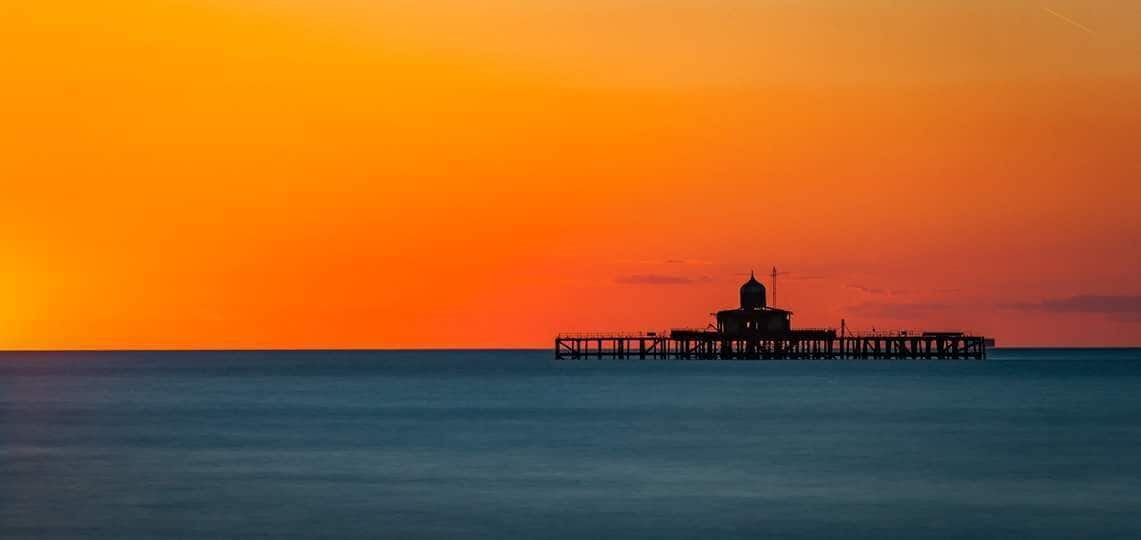 A pier extending into calm waters during sunset.