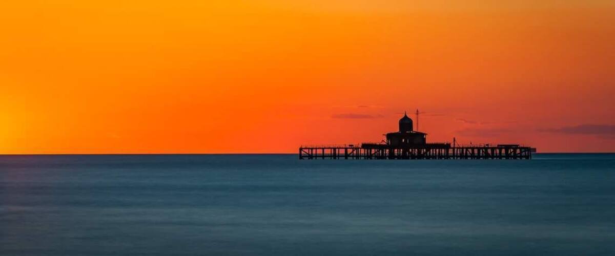 A pier extending into calm waters during sunset.