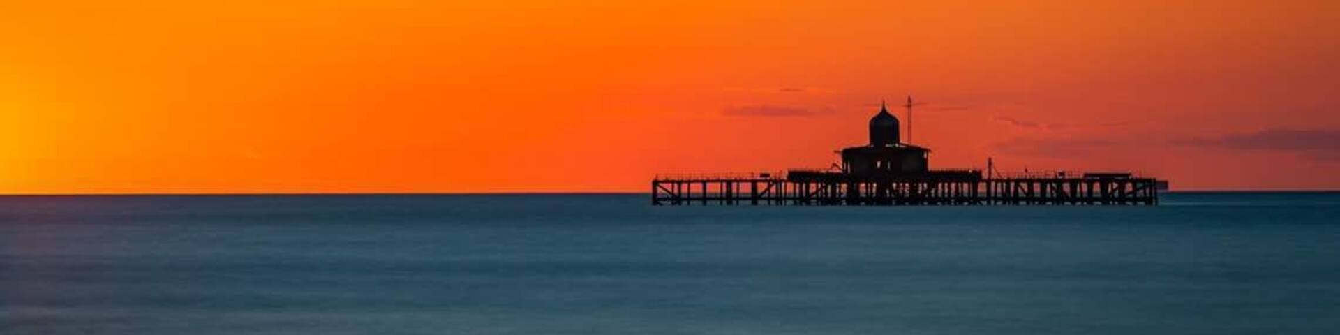 A pier extending into calm waters during sunset.
