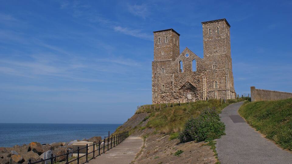 A stone church with two towers by the sea.