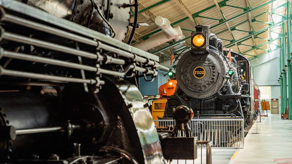 A steam locomotive with the number 7002, inside a covered railway station.