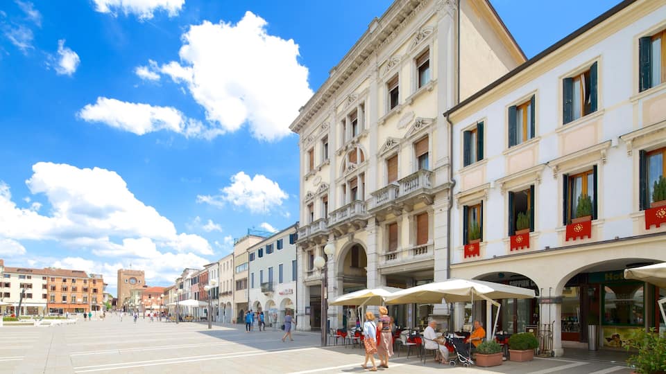 A sunny square with historic buildings, outdoor cafes, and a clear blue sky.