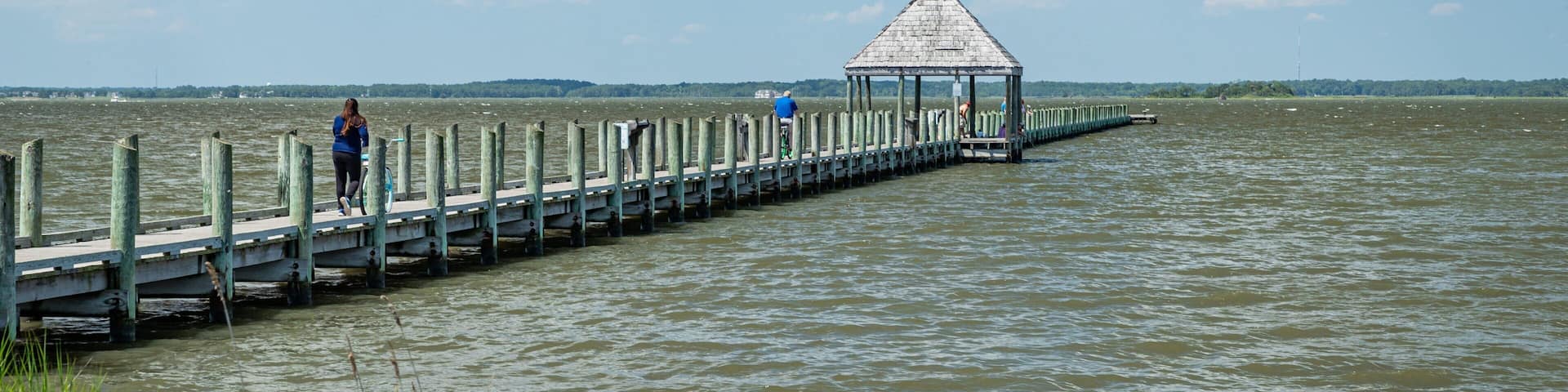 A wooden pier extending into a body of water with a gazebo at the end.