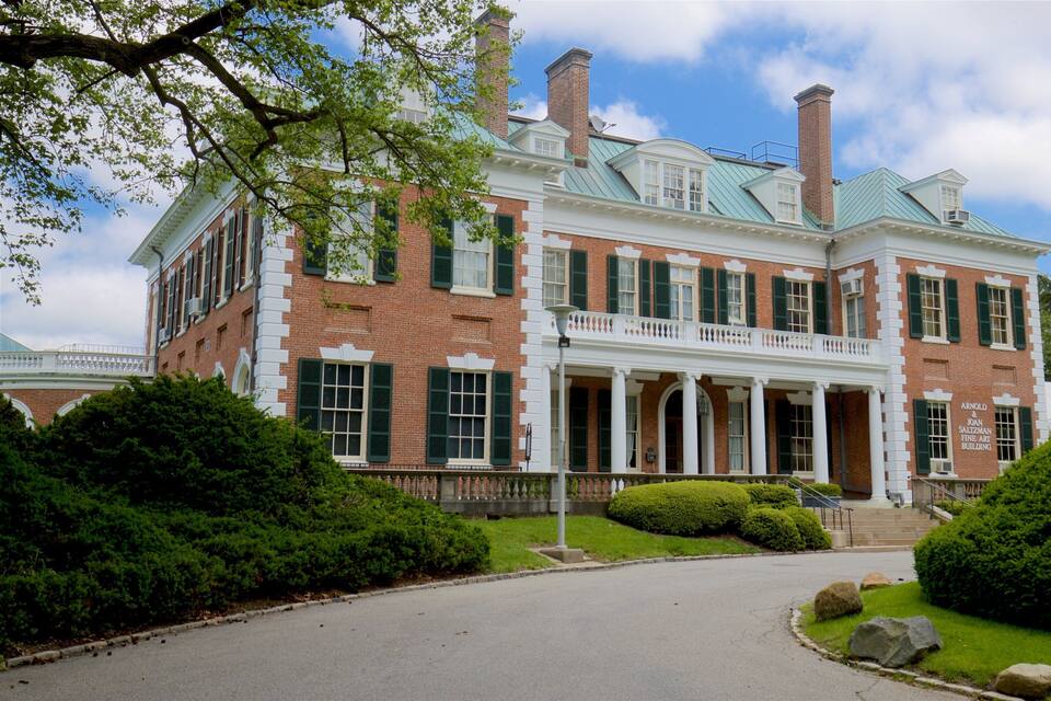 A large, historic brick building with a green roof and white columns.