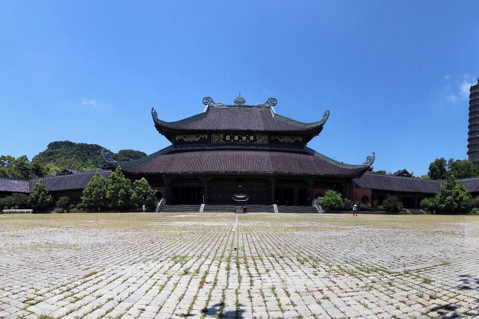 Um complexo de templos chineses tradicional, com um edifício central imponente, uma pagode e um pátio pavimentado.