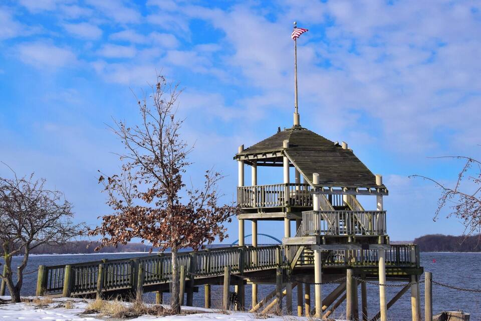 A wooden observation tower with an American flag on a pier extending into a lake.
