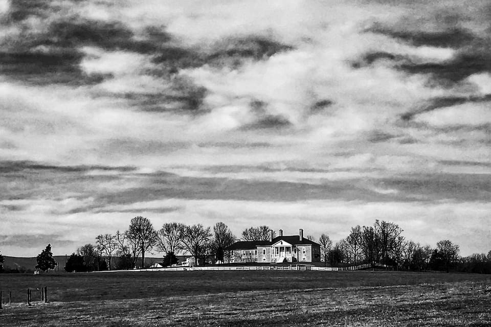 A large house in a field with a cloudy sky.