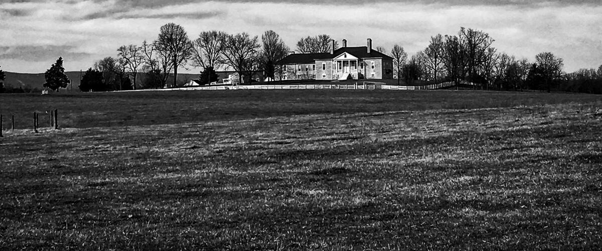 A large house in a field with a cloudy sky.