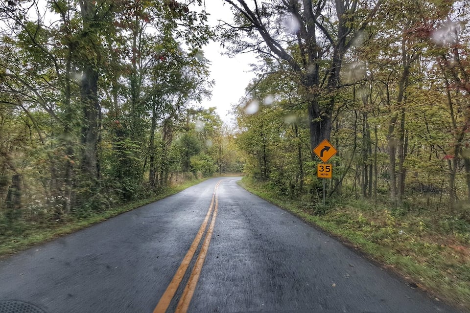 A two-lane road winding through a forest with a speed limit sign of 35 mph.