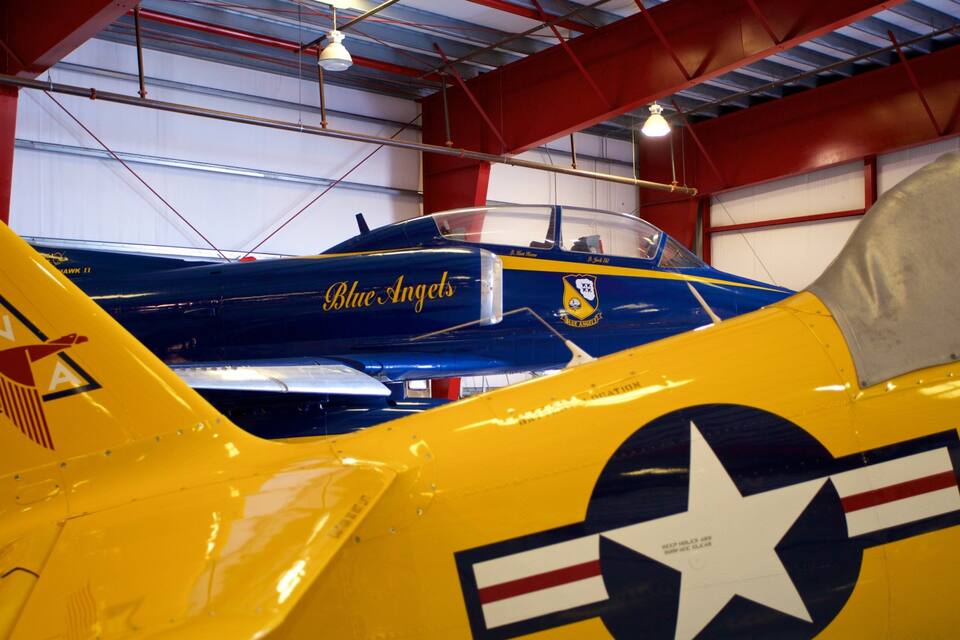 A yellow and blue vintage aircraft with the text "Blue Angels" and a star emblem.