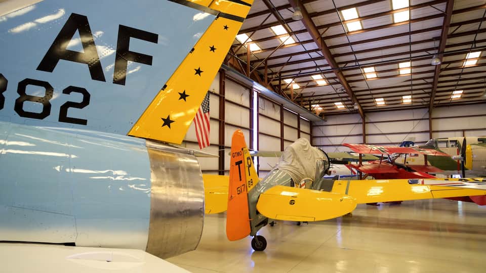 A yellow and blue vintage airplane with the registration number AF 882, parked inside a hangar with other aircraft.