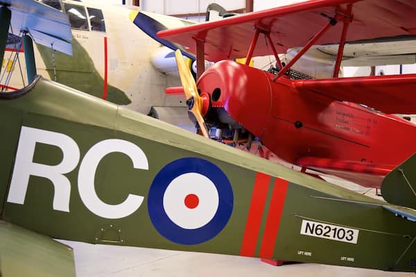 Il s'agit d'un avion militaire d'époque, immatriculé N62103, qui se distingue par sa couleur verte, son train d'atterrissage rouge et un cercle bleu et blanc sur le fuselage.