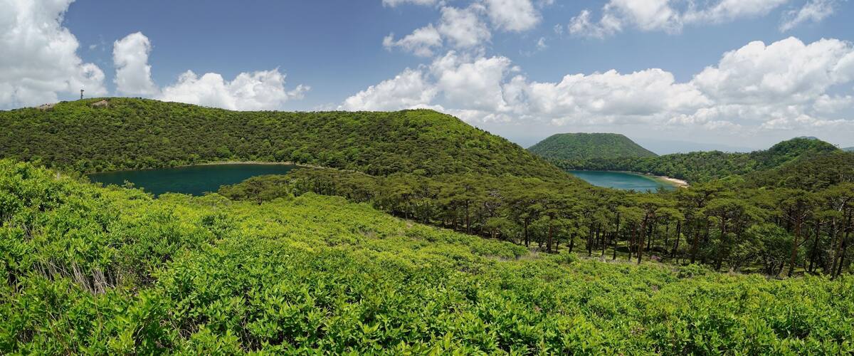 A lush green landscape with rolling hills, a clear blue sky, and a serene lake.