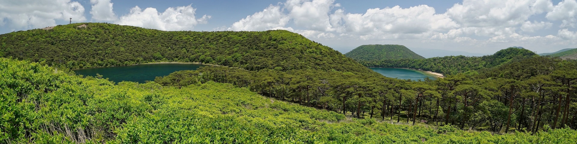 A lush green landscape with rolling hills, a clear blue sky, and a serene lake.