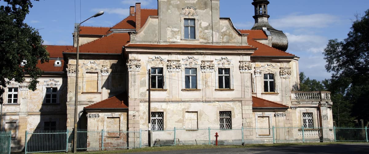 A historic building with ornate architecture, a red-tiled roof, and a prominent tower.