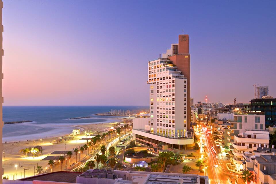 Eine Küstenstadtlandschaft mit einem markanten Hotel, Strand und städtischen Straßen im Abenddämmerung.