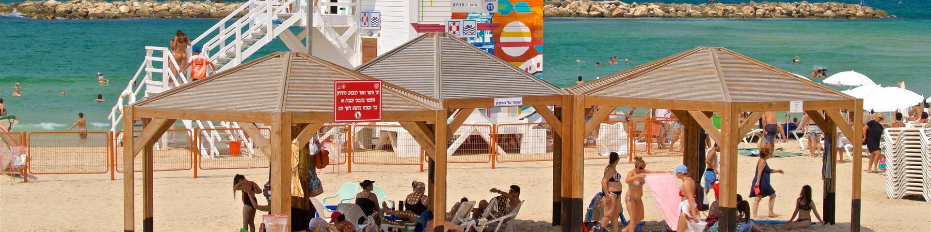 Una playa con torres de salvavidas, sombrillas y gente tomando el sol.