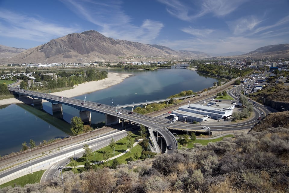 Eine Brücke über einem Fluss, einer Autobahn und einer gebirgigen Landschaft.