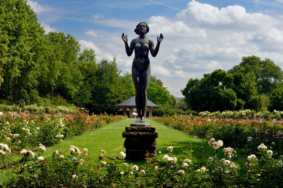 Eine Statue in einem Garten, im Hintergrund ein Pavillon.