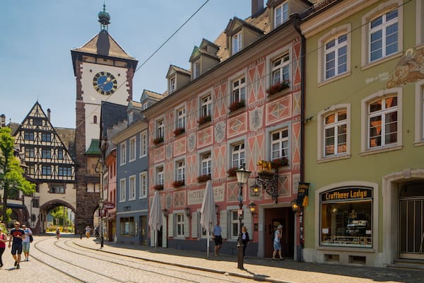 A historic European town with a prominent clock tower, colorful buildings, and a craft beer pub.